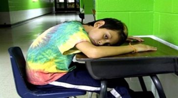 boy in detention in school all with head on desk