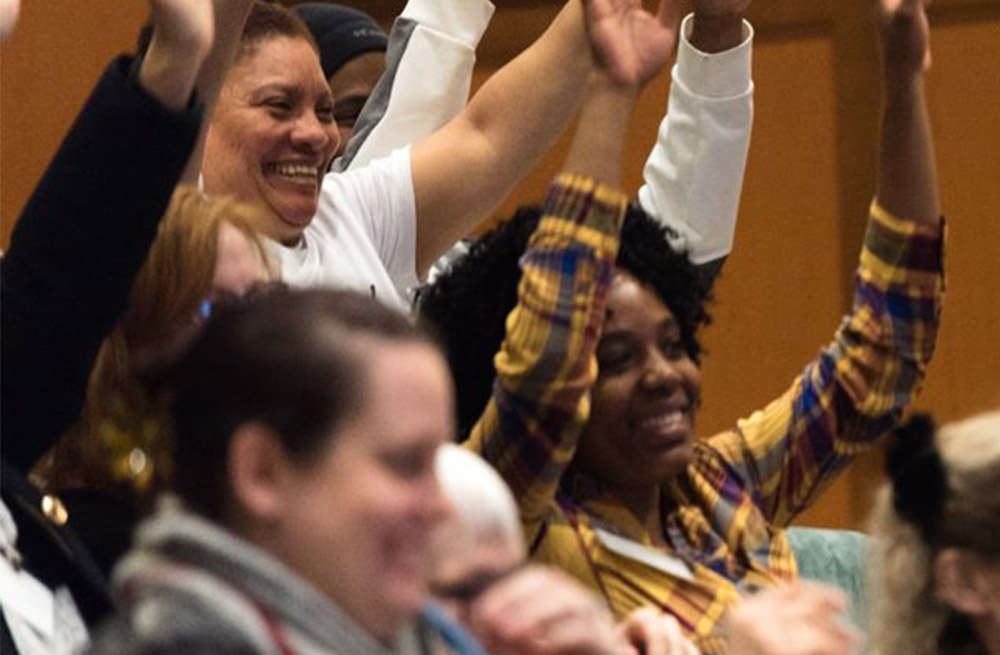 Women in an audience raising their hands