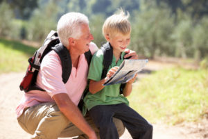 Senior man reading map with grandson on country walk