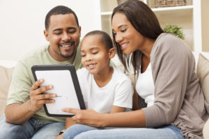 African American family, parents and son, having fun using tablet computer together