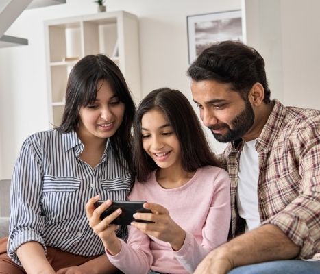 Latino mom, dad, and teen reading information off of a smart phone