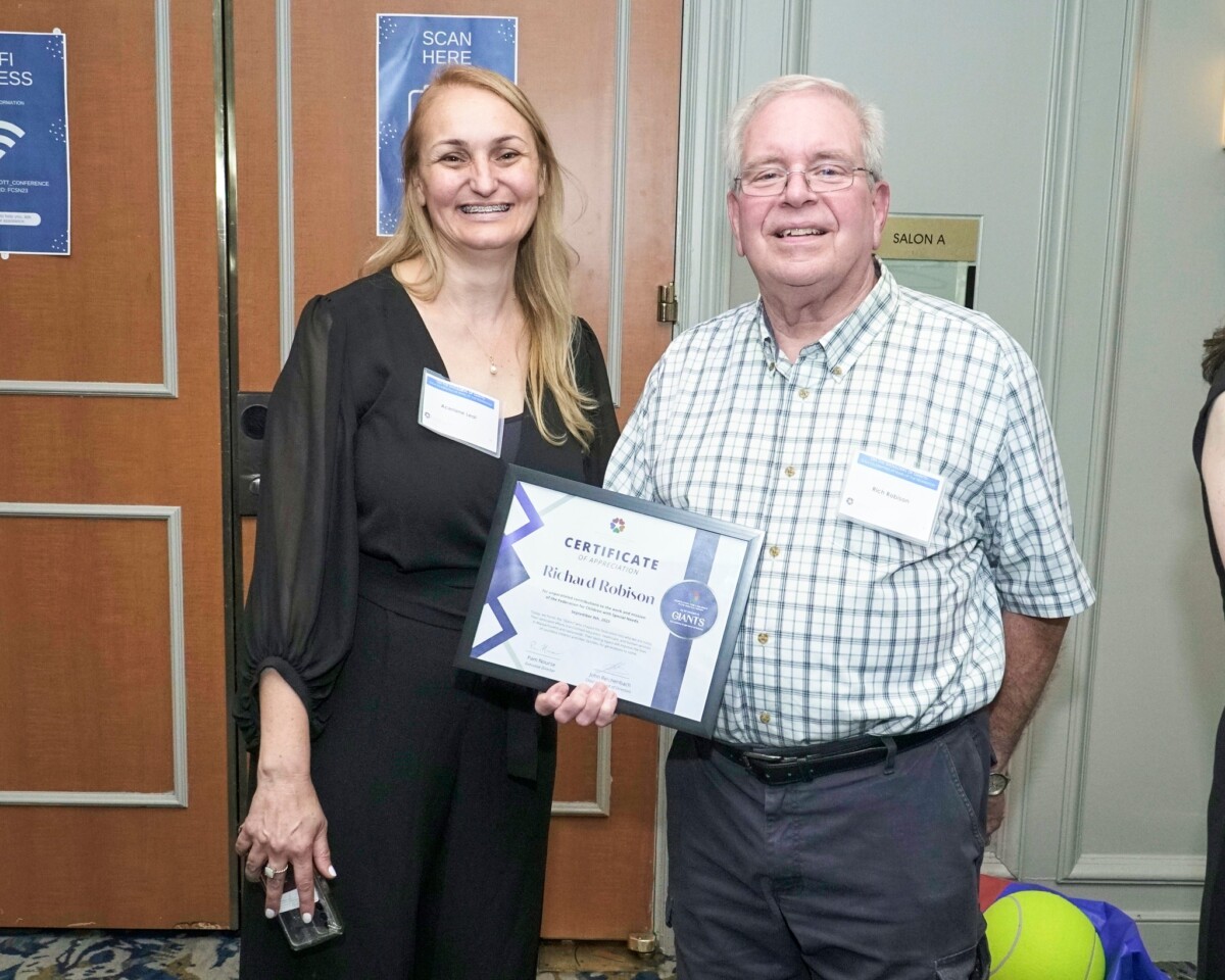 Former Executive Director Rich Robison holds his certificate, with staff member Aceriane Leal